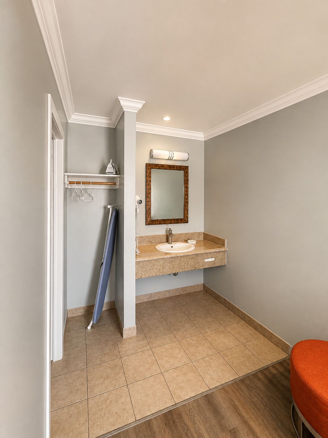 Un baño con lavamanos, espejo y perchero para toallas.