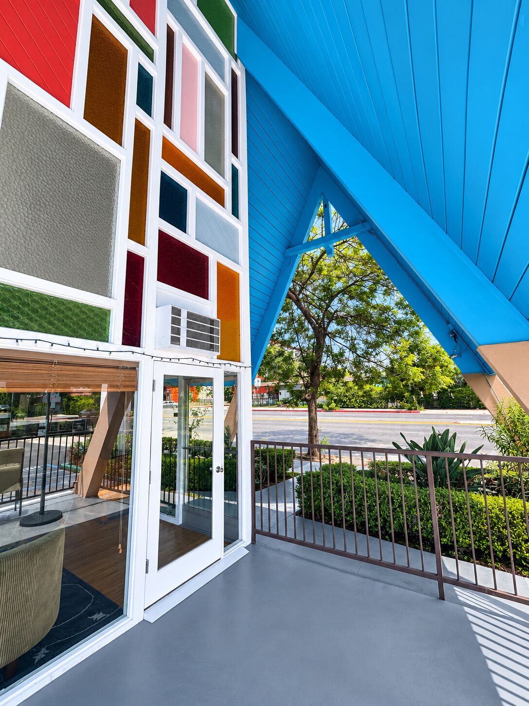 Um edifício moderno com fachada colorida e uma área externa coberta com guarda-corpo de metal.