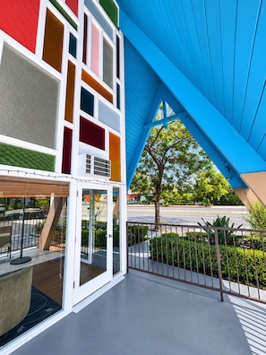 A modern building with a colorful facade and a covered outdoor area with a metal railing.