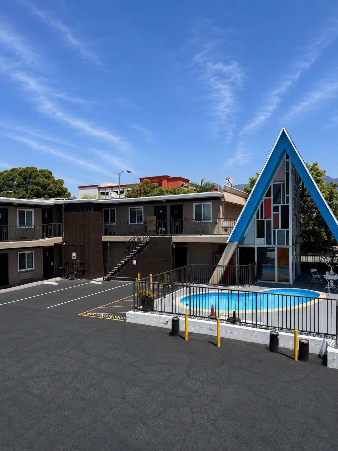 A hotel with a swimming pool, a parking lot, and a distinctive blue and white building.