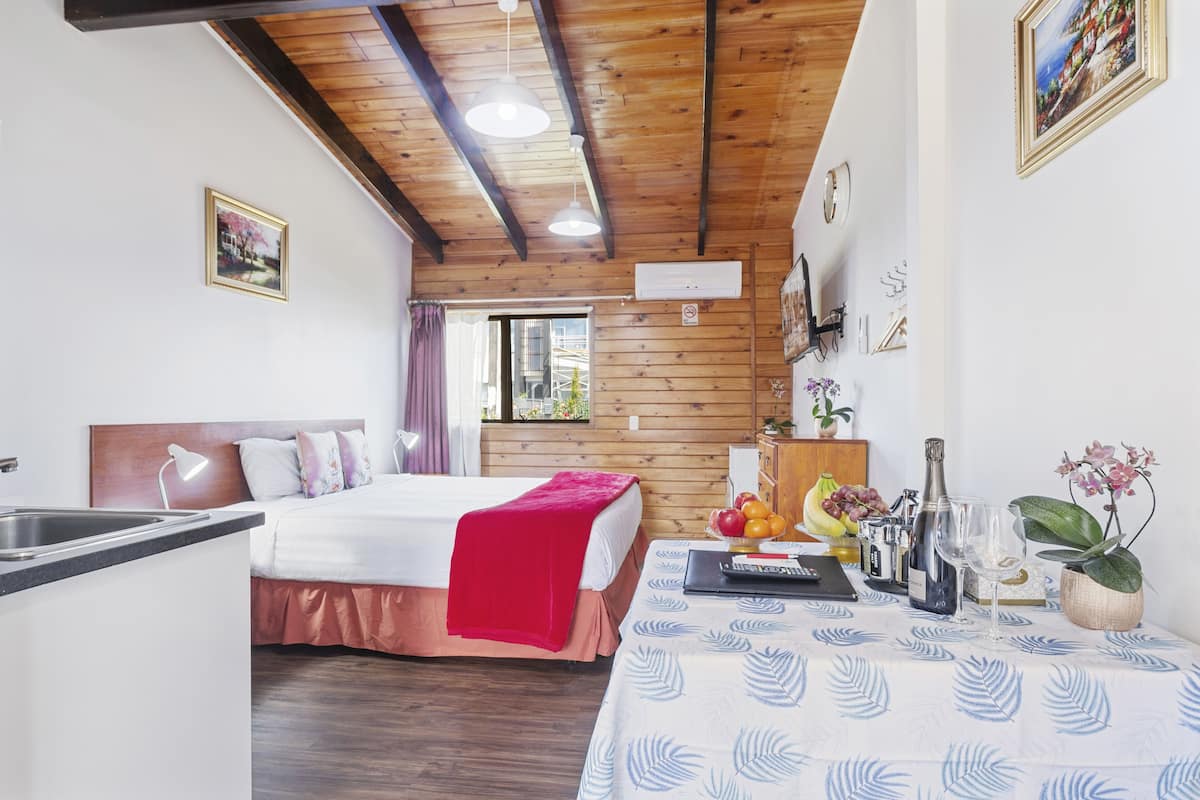 A bedroom with a bed, bedside table, and a window.