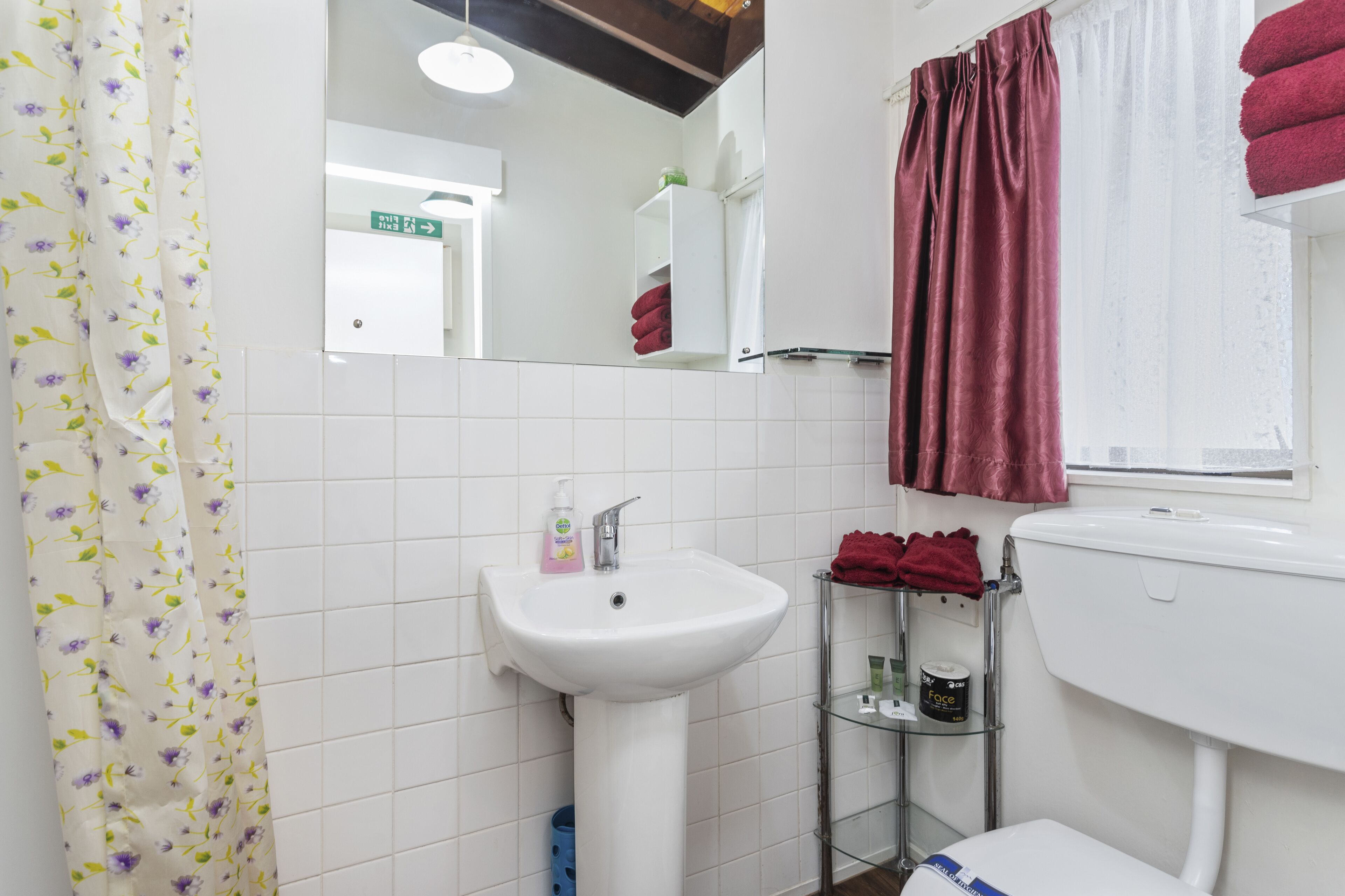 A bathroom with a white sink, a mirror, a toilet, and a shower curtain.