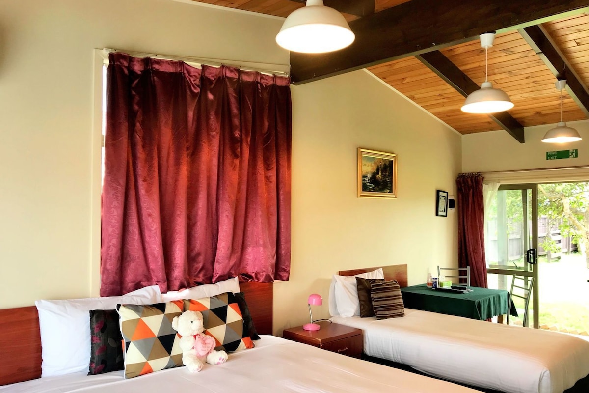 Une chambre d’hôtel avec deux lits, un plafond en bois, un tableau et une vue sur l’extérieur.