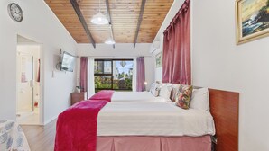 A bedroom with two beds, wooden ceiling beams, a TV, and a window with curtains. - Grange Motel (Auckland)
