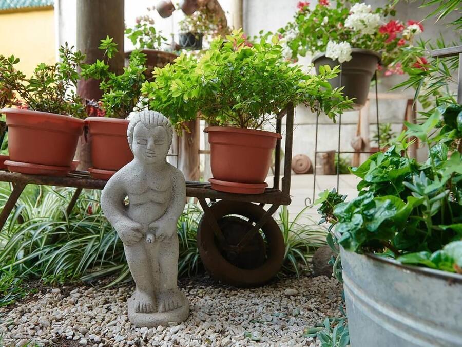 A garden with a statue, potted plants, and a metal cart.