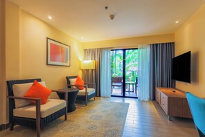 A hotel room with a sofa, armchair, TV, and a balcony with curtains. - Holiday Inn Resort Phuket Surin Beach by IHG (Choeng Thale)