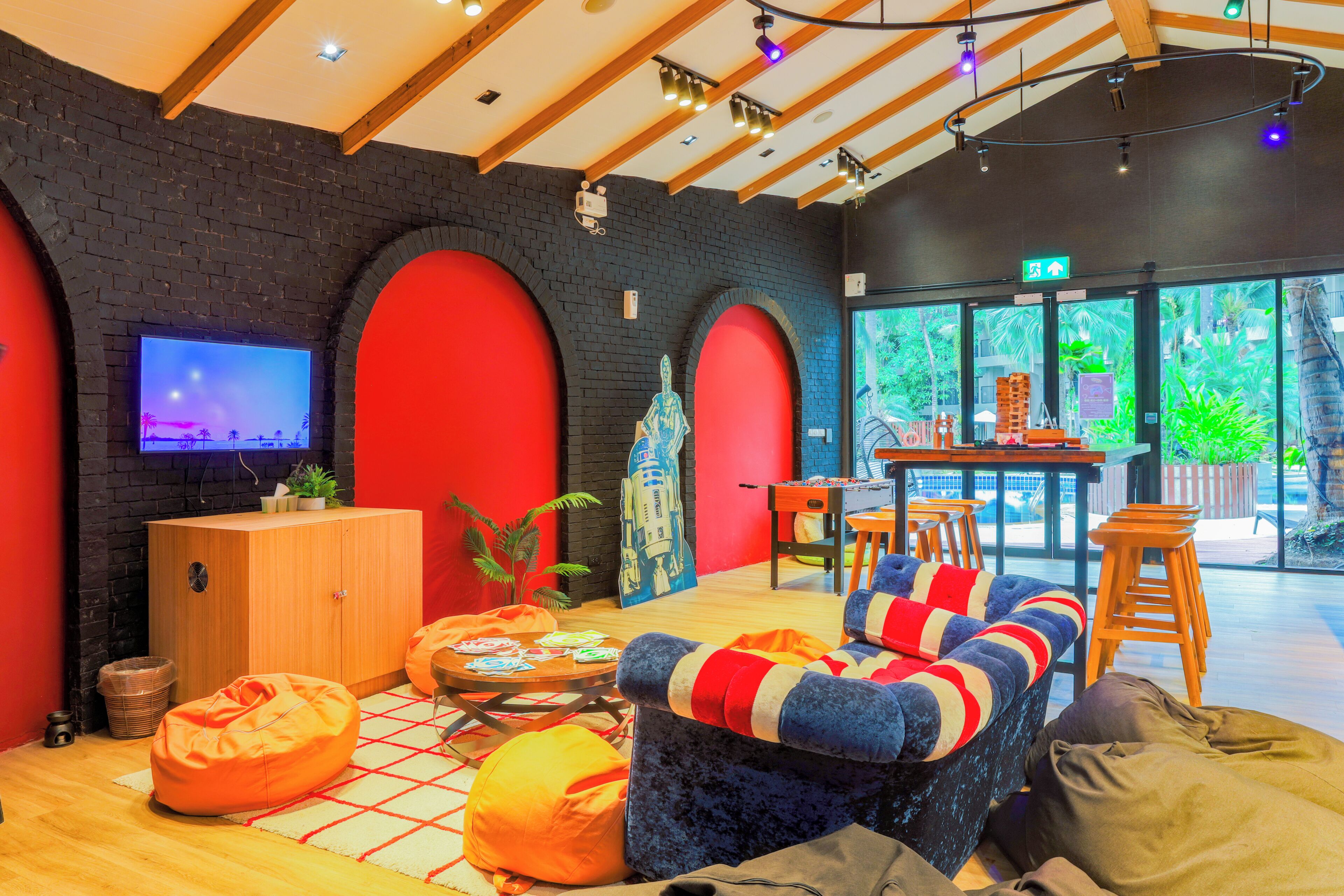 A modern interior with a foosball table, seating area, and a TV screen.