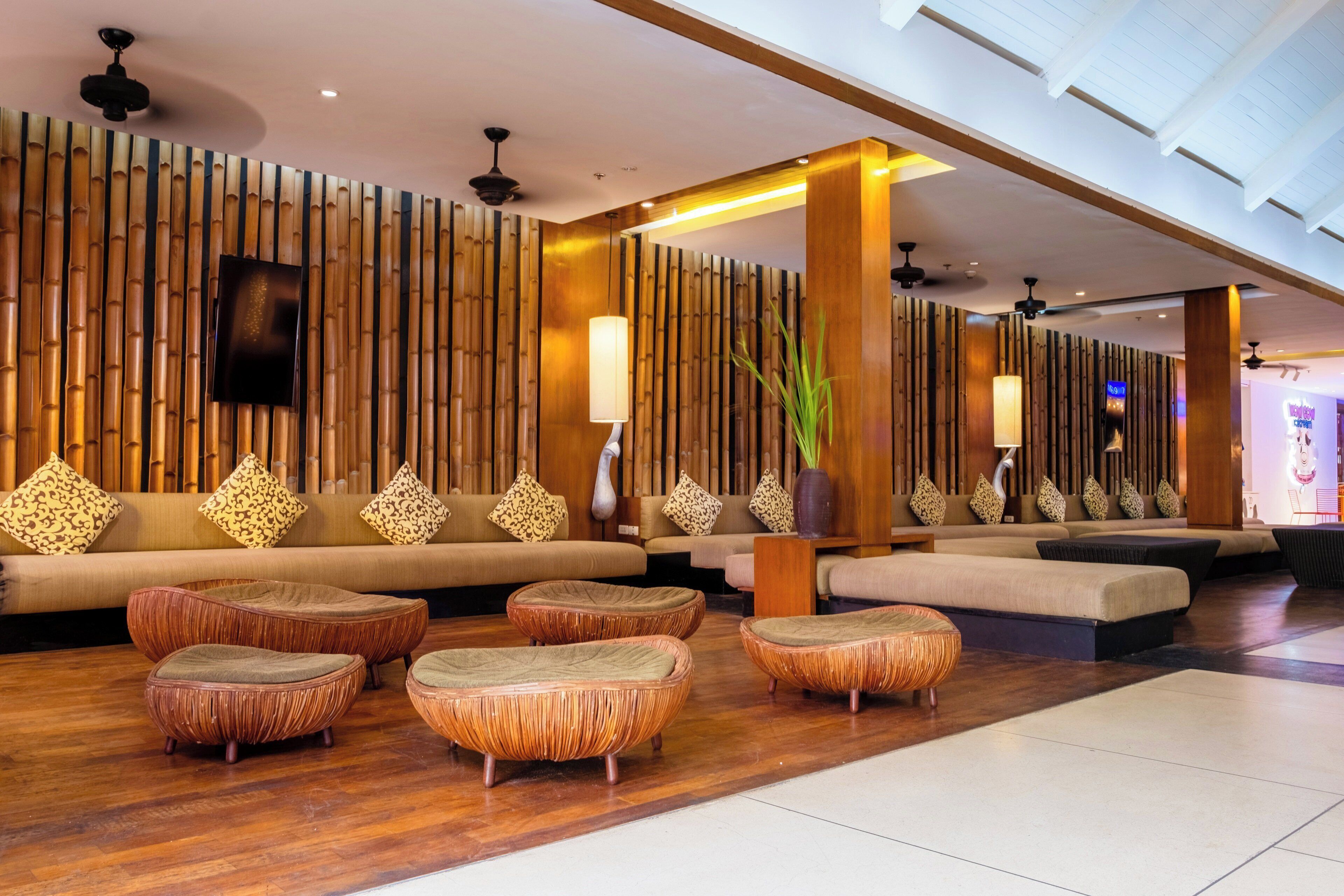 Un hall d’entrée avec un mur en bambou, des canapés et des fauteuils en rotin.
