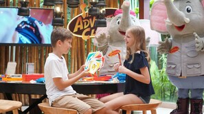 A child and an adult playing a card game with a mascot. - Holiday Inn Resort Phuket Surin Beach by IHG (Choeng Thale)