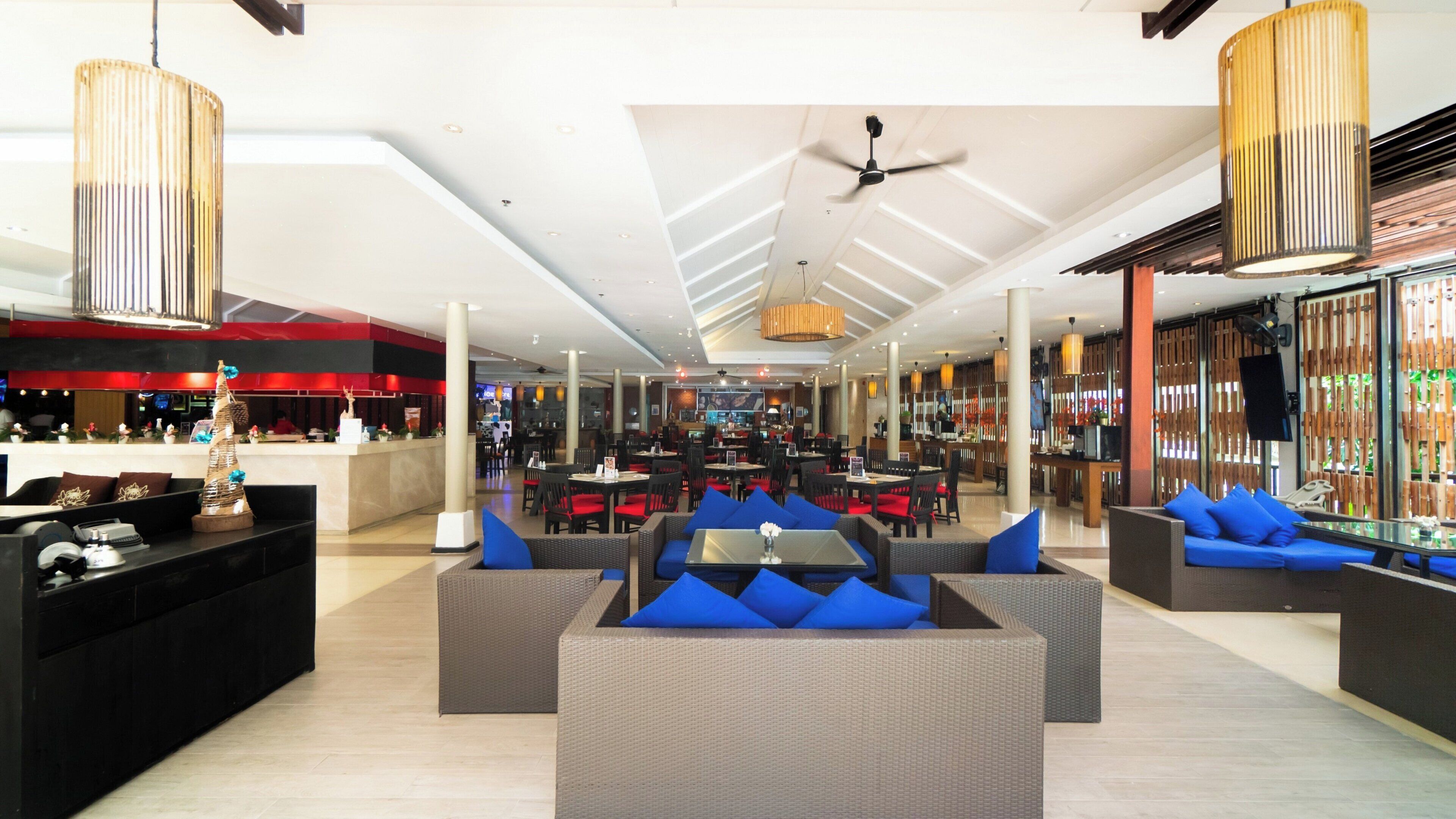 A spacious lobby with a high ceiling, seating areas with blue cushions, and a bar area with wooden partitions.