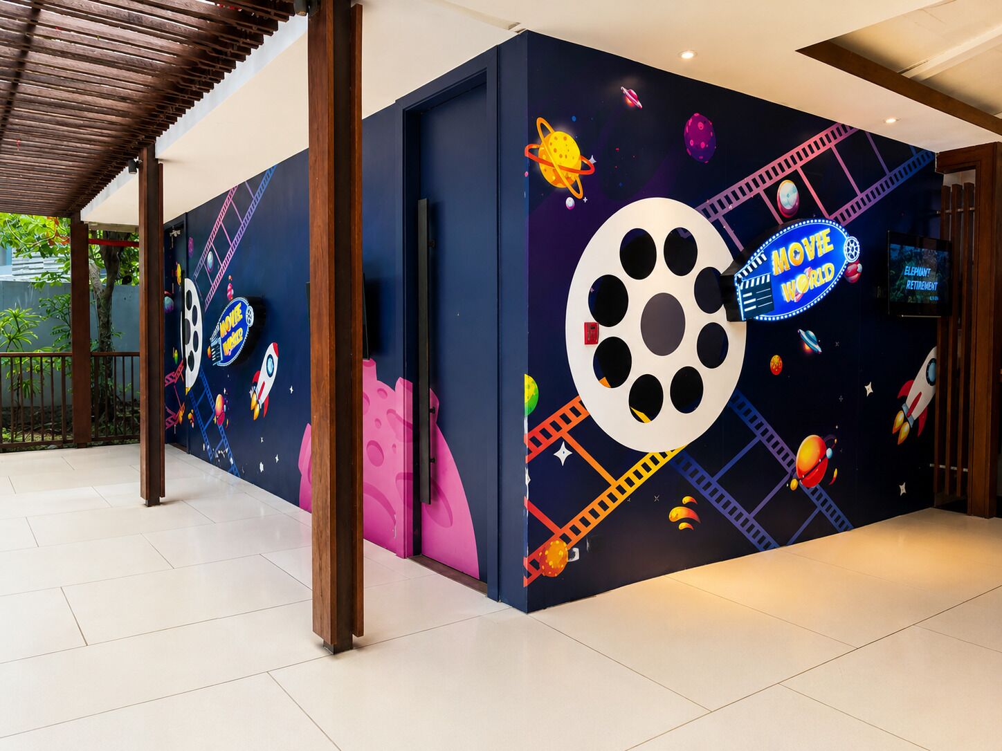 Un mur orné d’une fresque sur le thème de l’espace, comprenant une grande bobine de film et des planètes.