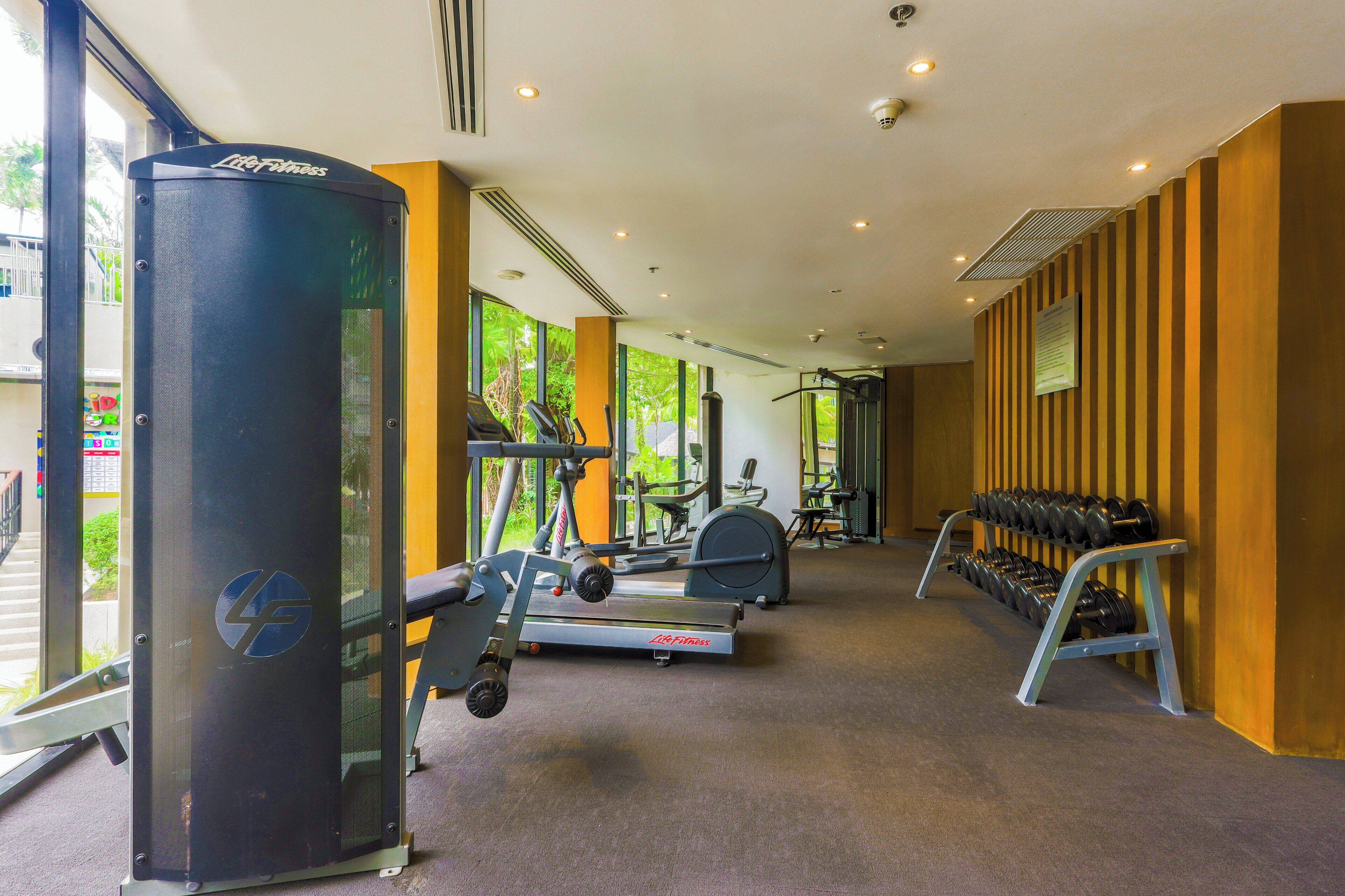 A gym with cardio equipment, weight machines, and a rack of dumbbells.