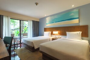 A hotel room with two beds, a desk, a chair, a lamp, and a painting of a beach scene. - Holiday Inn Resort Phuket Surin Beach by IHG (Choeng Thale)