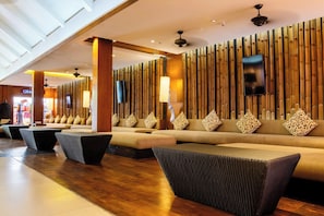 A modern lobby with a long reception desk, a sofa area with patterned cushions, and a bamboo wall design. - Holiday Inn Resort Phuket Surin Beach by IHG (Choeng Thale)
