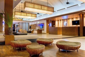 A modern hotel lobby with a reception desk, seating area, and a large television screen. - Holiday Inn Resort Phuket Surin Beach by IHG (Choeng Thale)