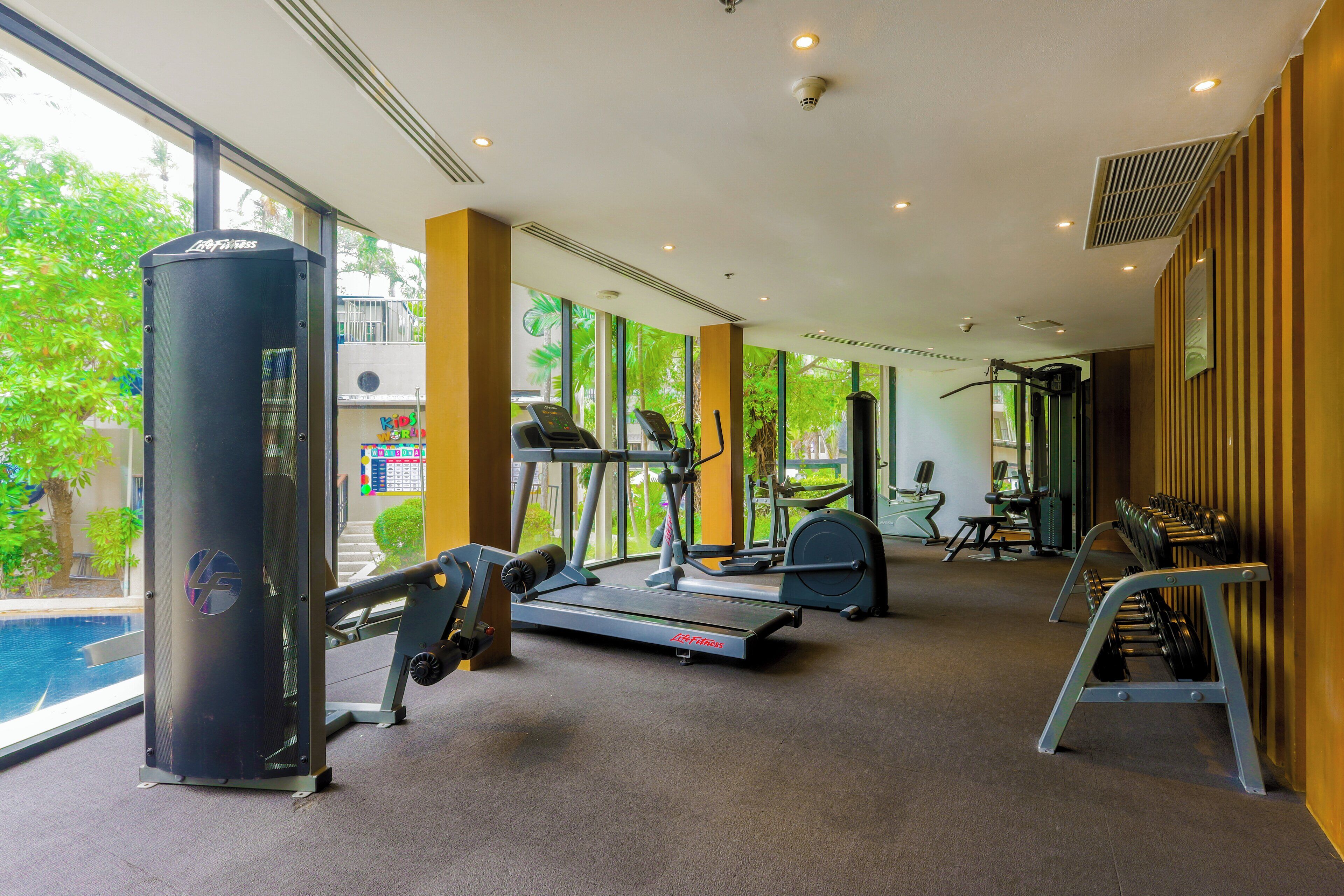 Une salle de sport équipée de machines de cardio, de bancs de musculation et d’un grand ballon d’exercice.
