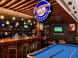 A bar area with a pool table, wooden furniture, and a sign for Champions Sin Beach Bar & Grill. - Holiday Inn Resort Phuket Surin Beach by IHG (Choeng Thale)