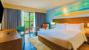 A hotel room with a large bed, a desk, a chair, and a view of the outdoors.