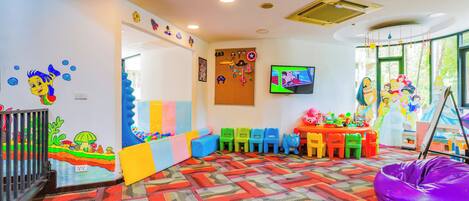 Un salón de juegos para niños con juguetes coloridos, una zona de recreación y un televisor.