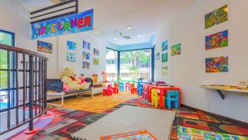 Une salle de jeux pour enfants avec des meubles colorés, des jouets éducatifs et des œuvres d’art accrochées aux murs.