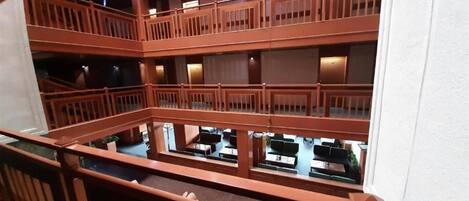A multi-level atrium with wooden railings and a central open space with tables and chairs.