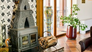 A room with a traditional wood-burning stove, a colorful vase, and a potted plant. - Regina Hotel (Druskininkai)