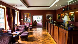 A hotel lobby with a bar area, seating with cushioned chairs, and a tiled floor. - Regina Hotel (Druskininkai)