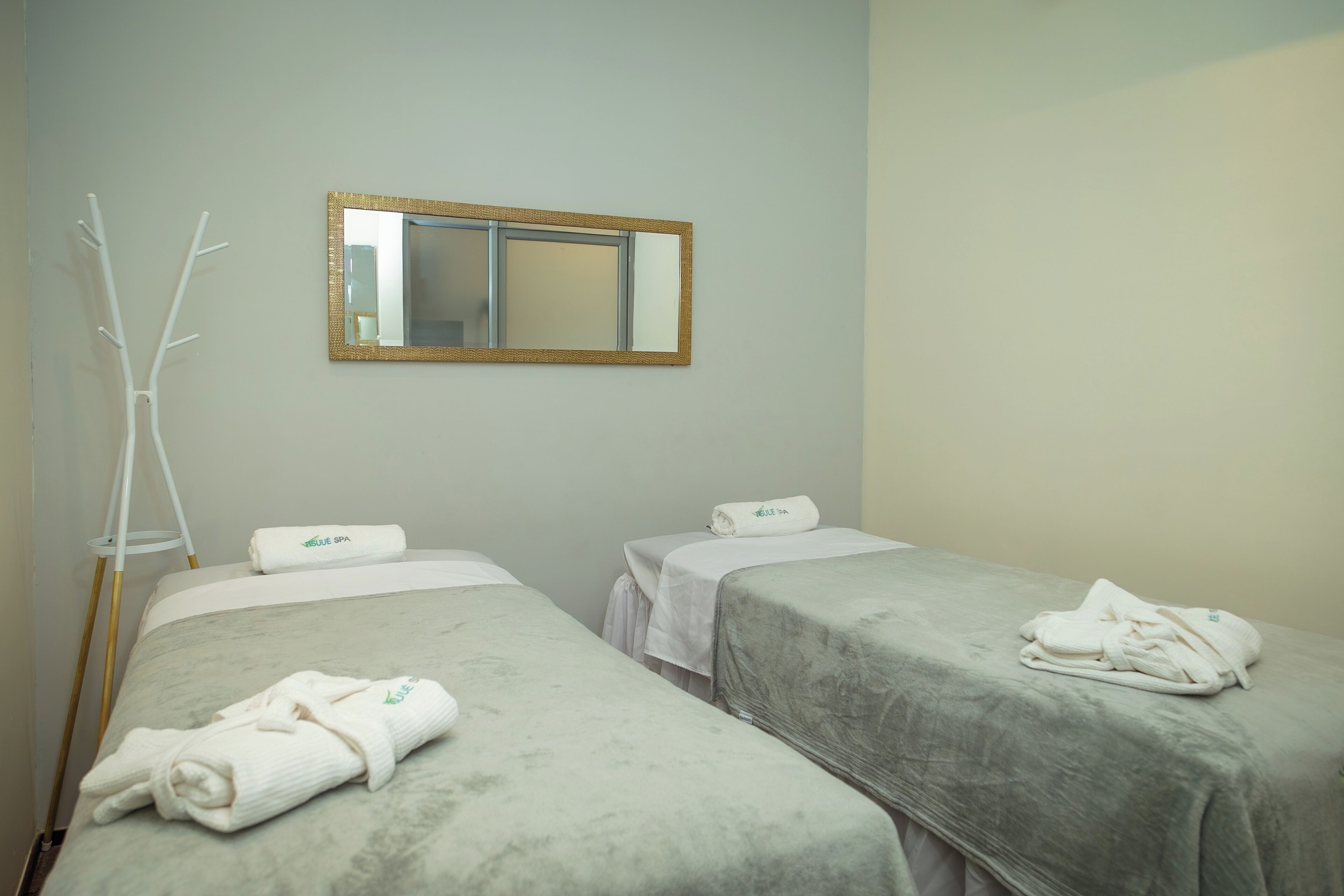 Habitació d'hotel amb dos llits, un mirall i un penjador blanc per tovalloles.