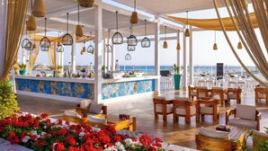 An outdoor seating area with wooden furniture, hanging wicker lamps, and a view of the sea. - Rixos Sharm El Sheikh Adults Only 18 + (Sharm El Sheikh)
