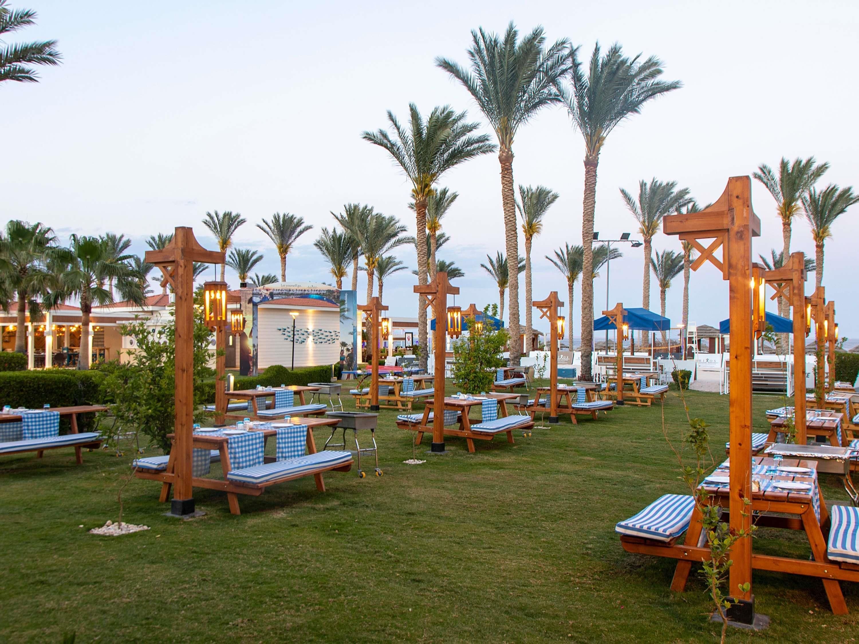 Un resort con zonas de estar al aire libre, palmeras y un edificio con un cartel.