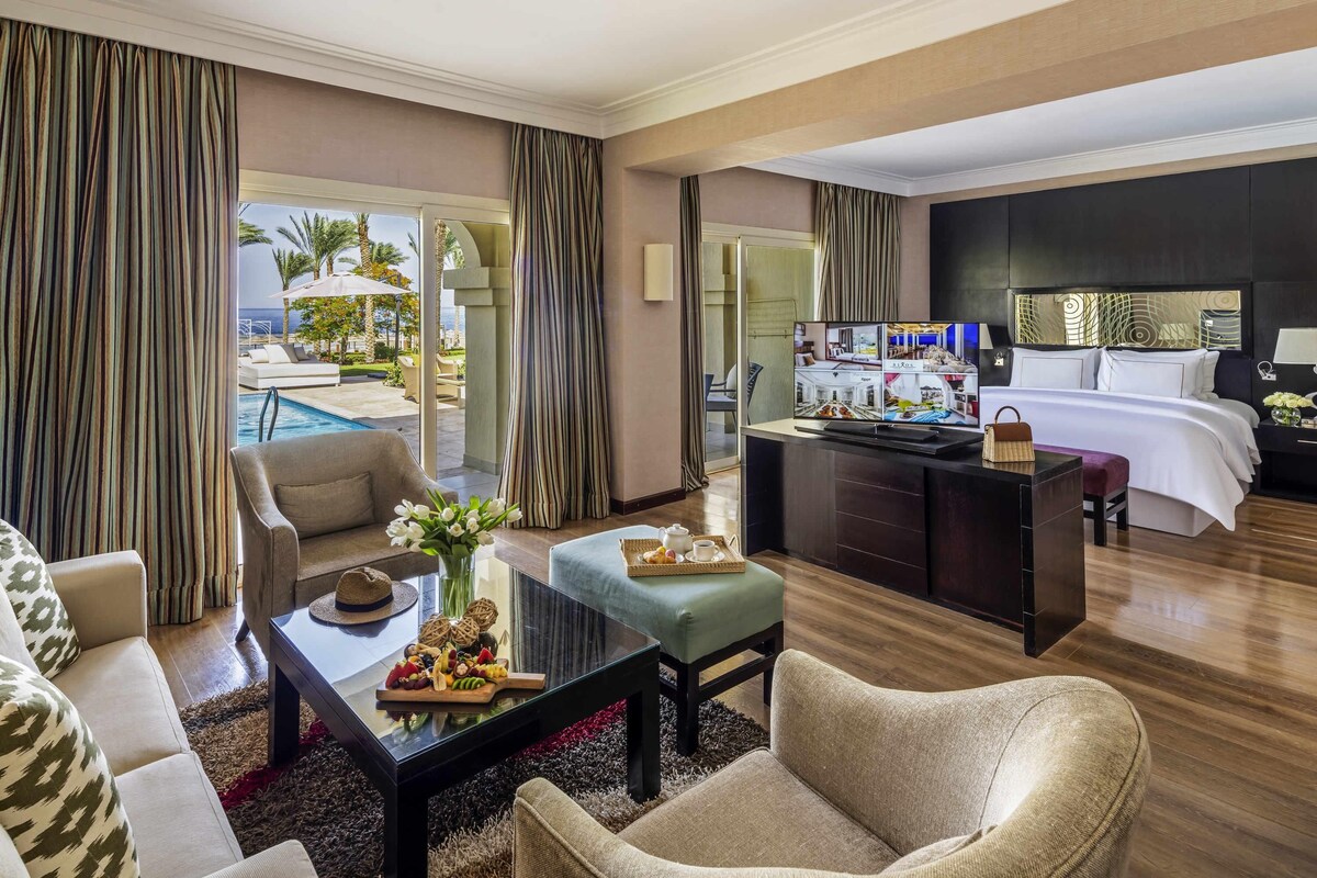 A hotel room with a pool view, a dining area, and a bed.