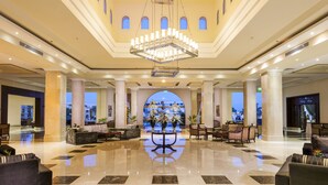 A spacious lobby with a large chandelier, comfortable seating, and a view of the cityscape through a large arched window. - Rixos Sharm El Sheikh Adults Only 18 + (Sharm El Sheikh)