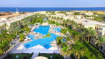 Un resort con una piscina central grande, varias piscinas más pequeñas y vistas al mar.