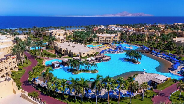 A resort with a large central pool, palm trees, and a view of the ocean. - Rixos Sharm El Sheikh Adults Only 18 + (Sharm El Sheikh)