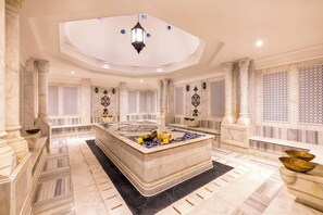 Une salle de bain luxueuse avec une baignoire en marbre, un grand miroir et un luminaire encastré au plafond.