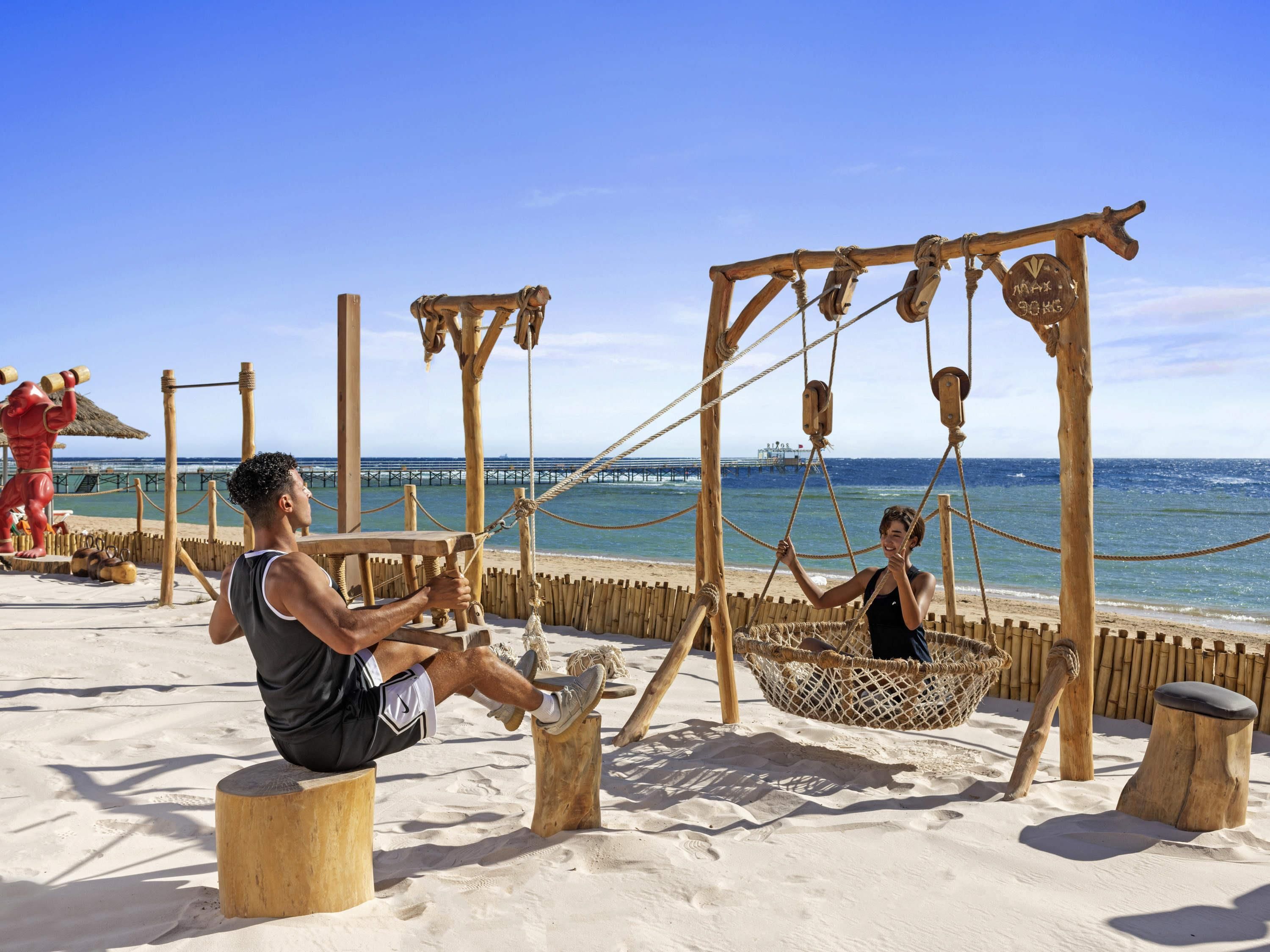 Una playa con columpios de madera y una torre de salvavidas.