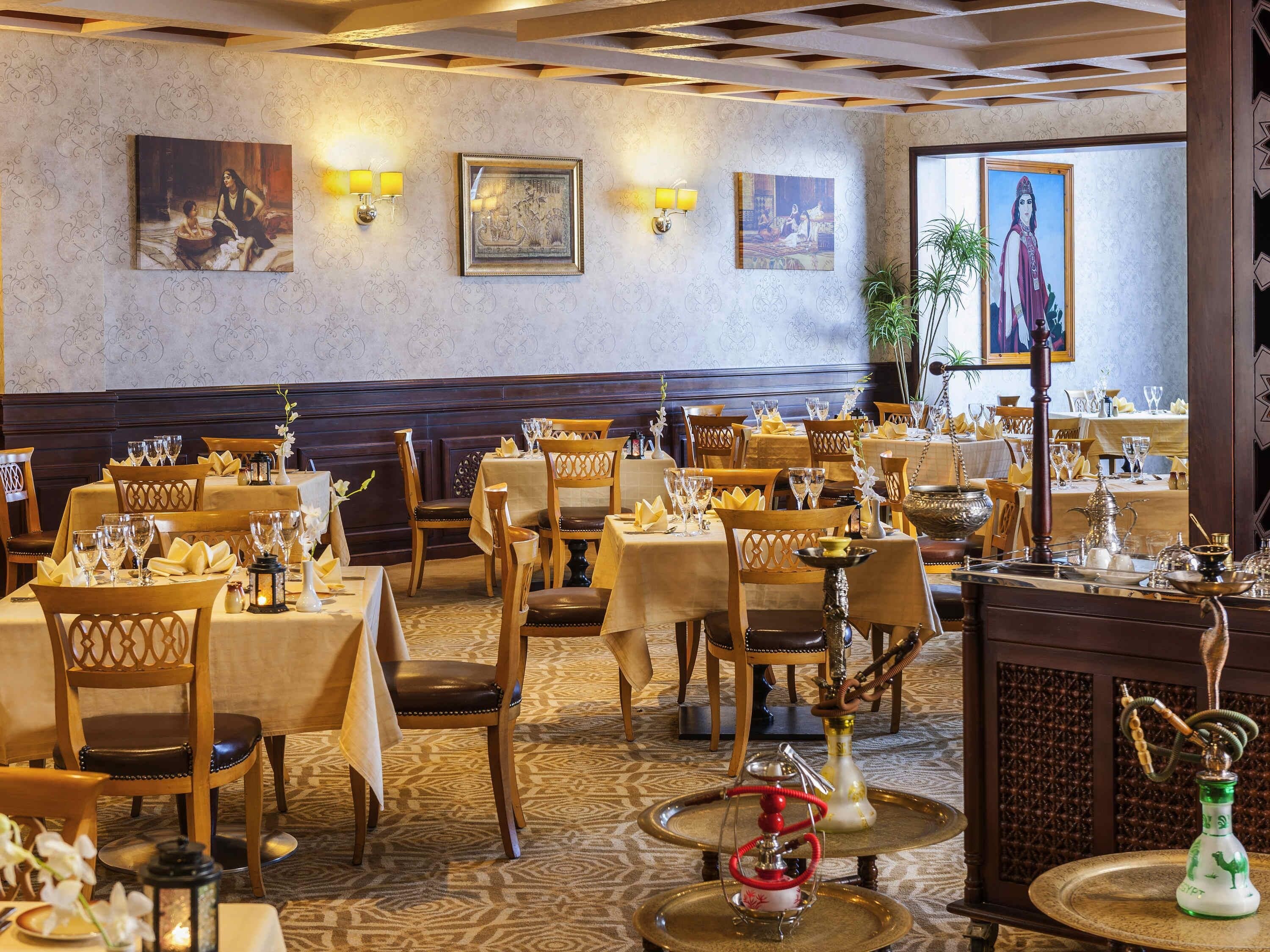 Un restaurante con varias mesas, sillas y distintos tipos de vajilla, incluyendo vasos y cubiertos.
