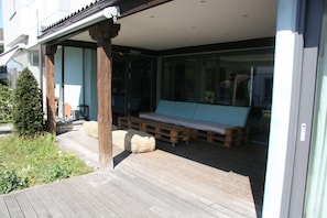 Ein überdachter Außenbereich mit Holzbänken und einer gepolsterten Couch.