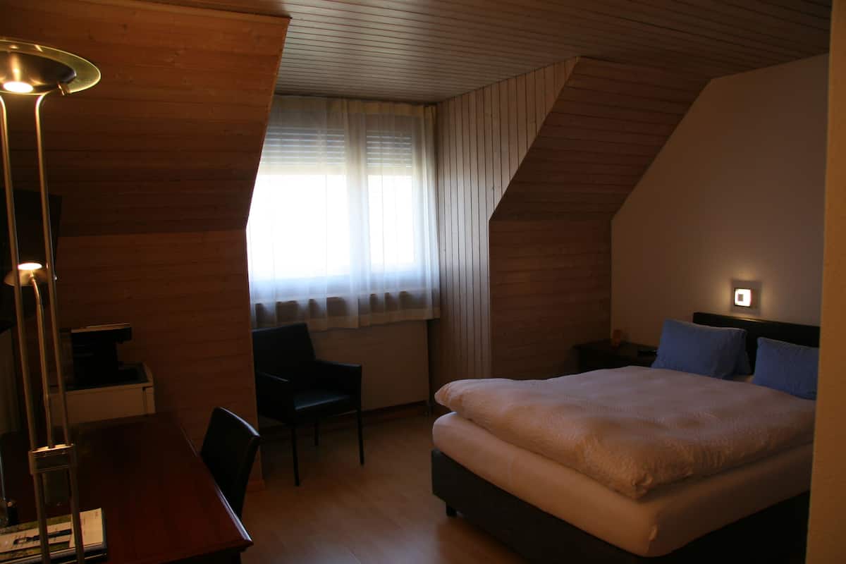 Makuuhuone, jossa on sänky, työpöytä, tuoli ja lamppu.