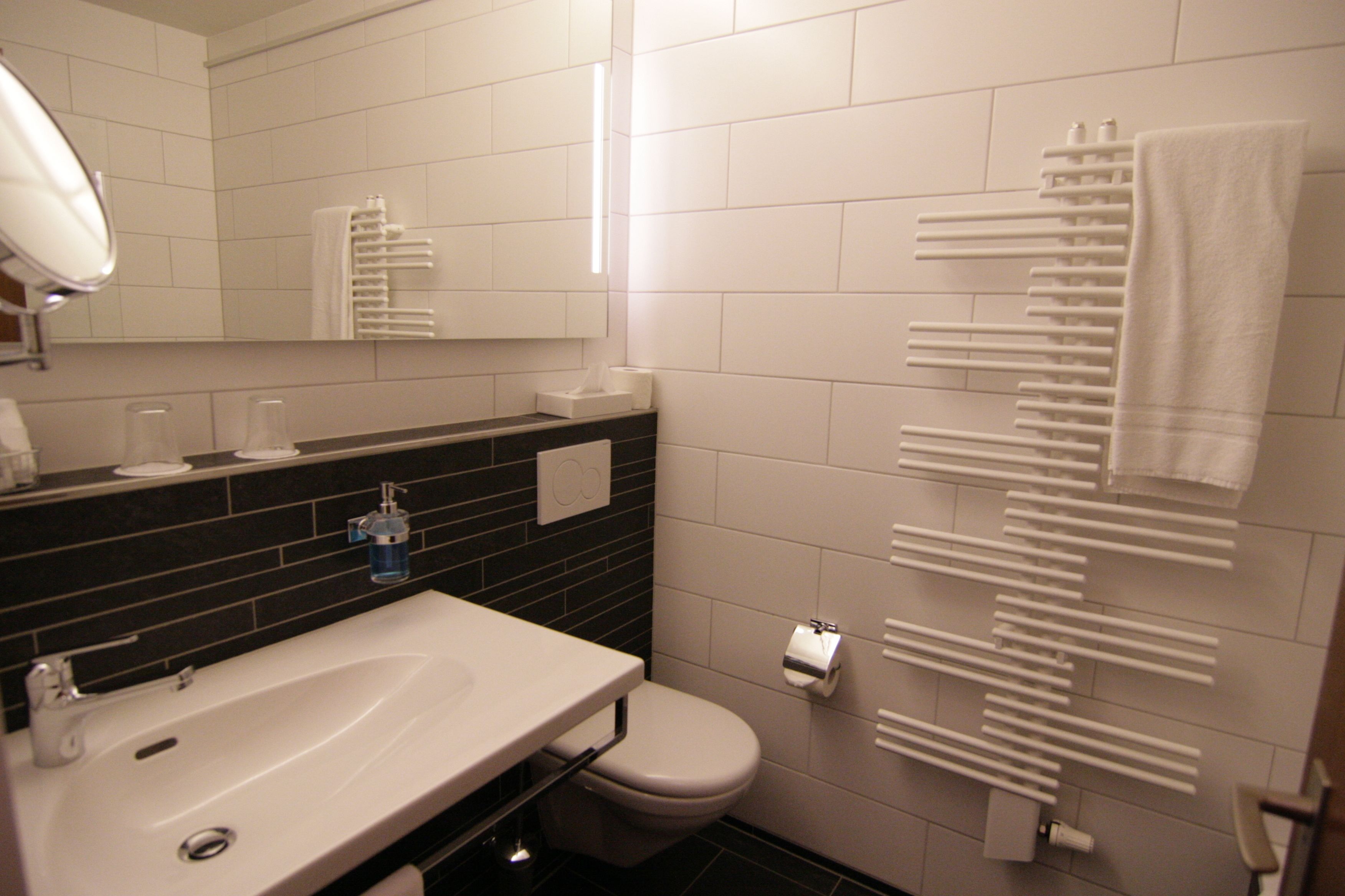 A modern bathroom with a white sink, toilet, and towel rack.