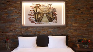 A neatly made bed with white linens, a dark headboard, and a framed picture of a tunnel on the wall. - Hotel Eremitage (Arlesheim)