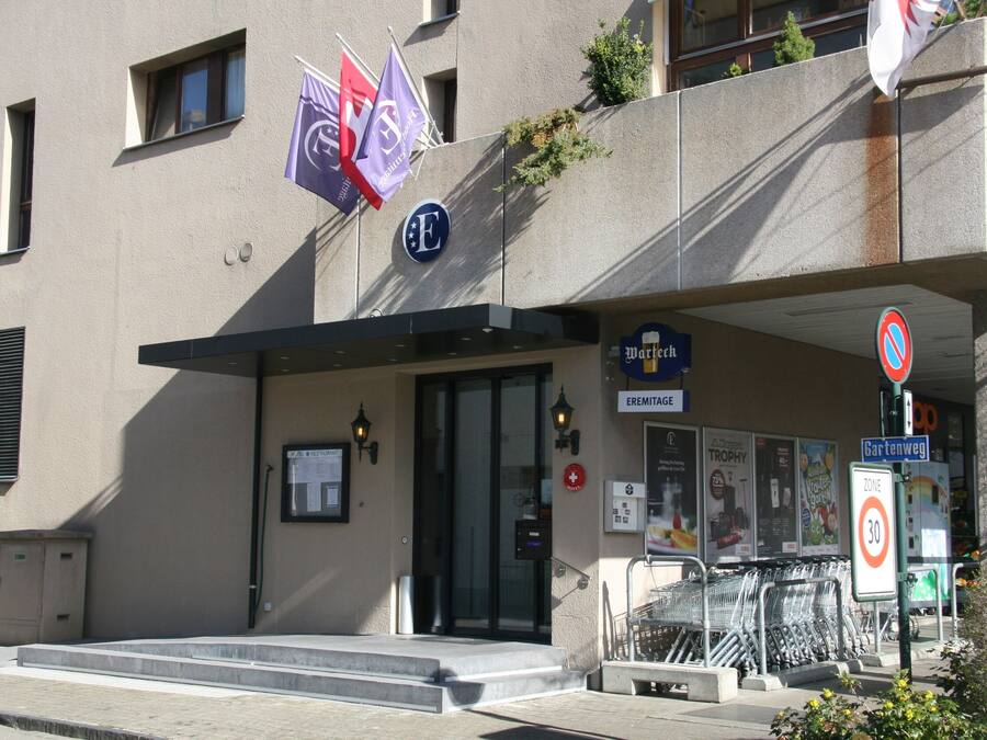 A building with a sign indicating a speed limit of 30, a no parking sign, and a visible entrance with steps leading up to the door.