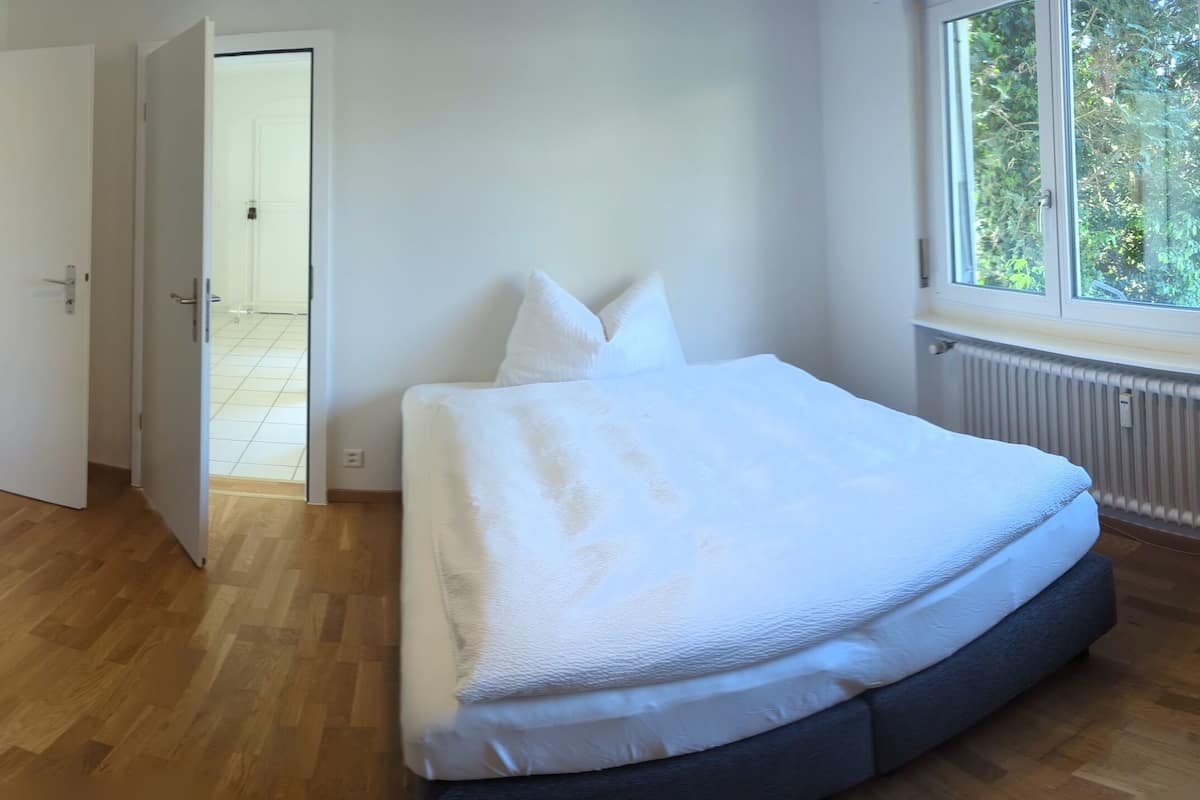 Hotellihuone, jossa on sänky, työpöytä, tuoli ja mikroaaltouuni.