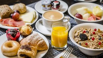 A breakfast setting with various food items including pastries, fruits, and a glass of orange juice.