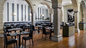 Een ruime restaurantruimte met hoge plafonds, gestreepte wanden en een bar in het midden.