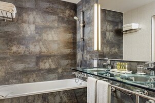 Un baño moderno con un lavamanos con recinto de vidrio, una bañera independiente y un espejo grande.