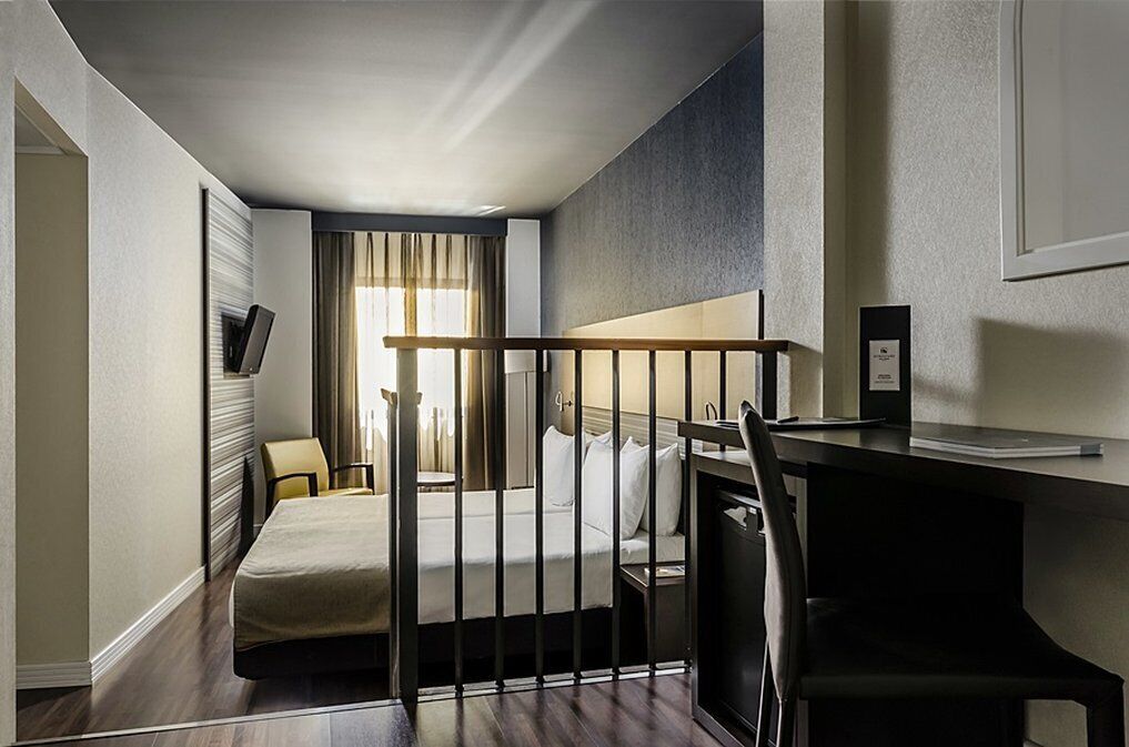 A hotel room with a bed, a desk, and a chair.
