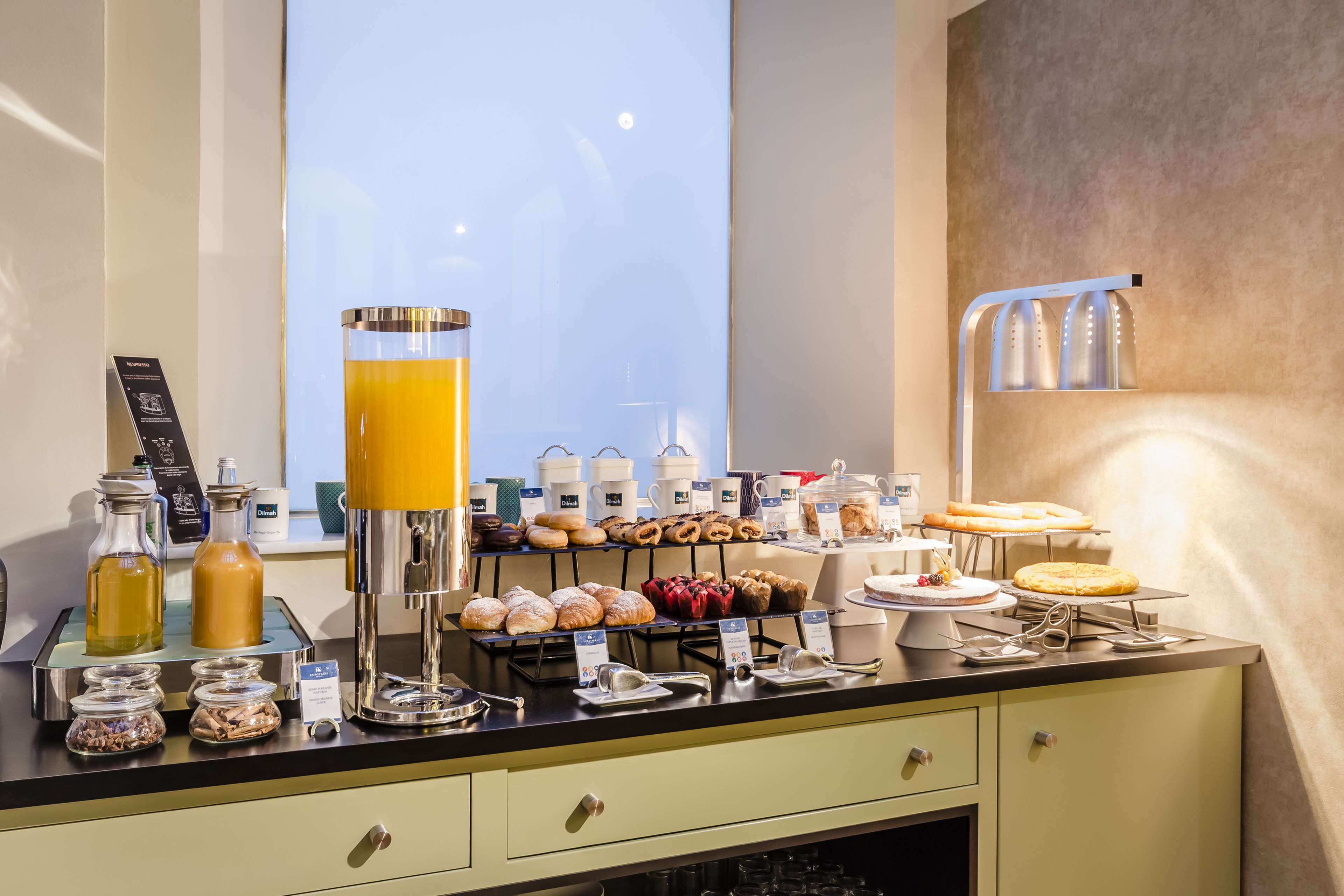 Un buffet de petit-déjeuner proposant diverses pâtisseries, une machine à café et un distributeur de jus.