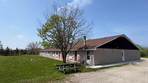 A single-story building with a large garage, a picnic table, and a tree in front. - Huron Coast INN (Kincardine)