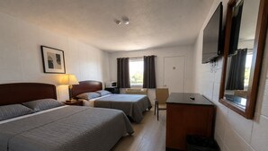 A hotel room with two beds, a desk, a chair, a TV, and a picture on the wall.